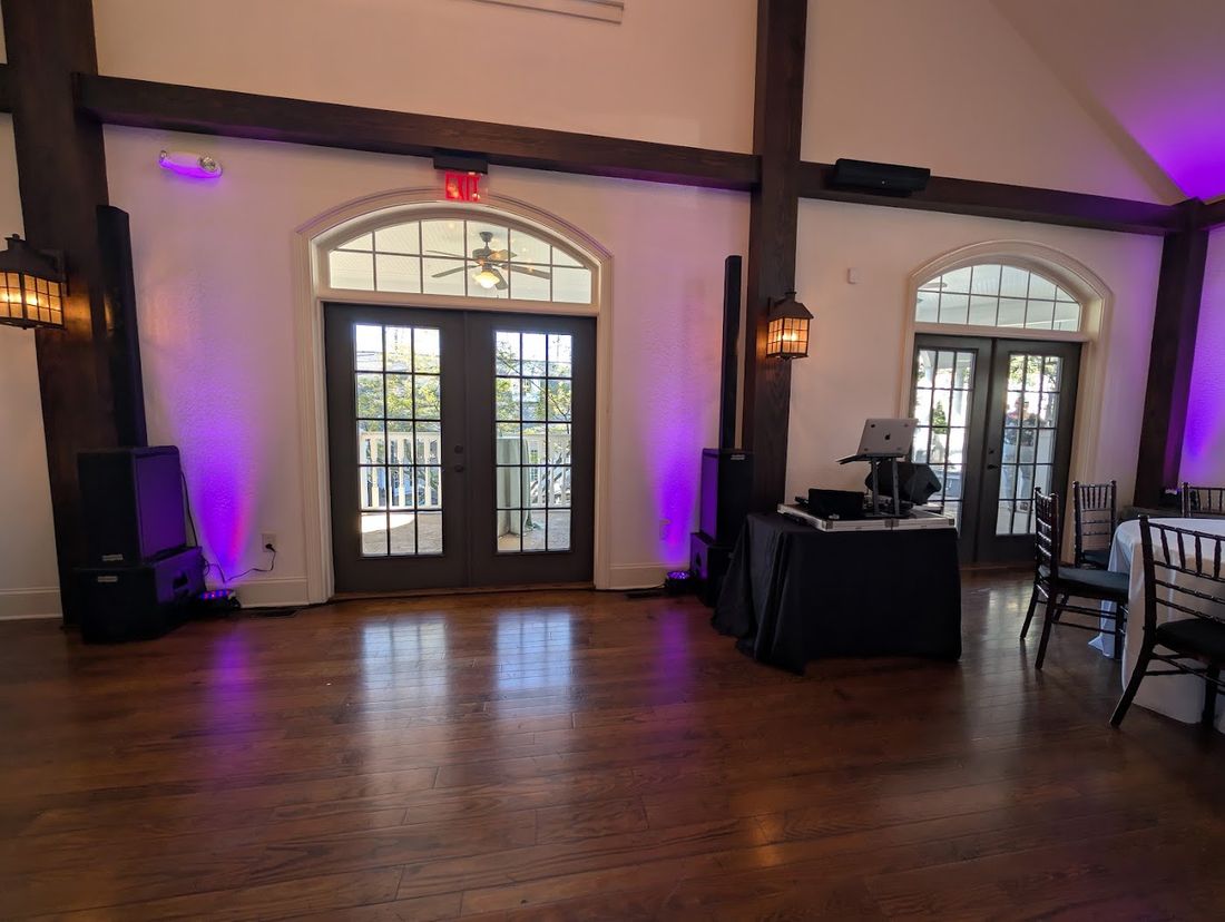 Room with purple uplighting on the walls and a DJ table